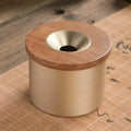 Retro-style solid copper ashtray with a wooden lid featuring a centre hole, shown in brass and black wood or brass and red wood.