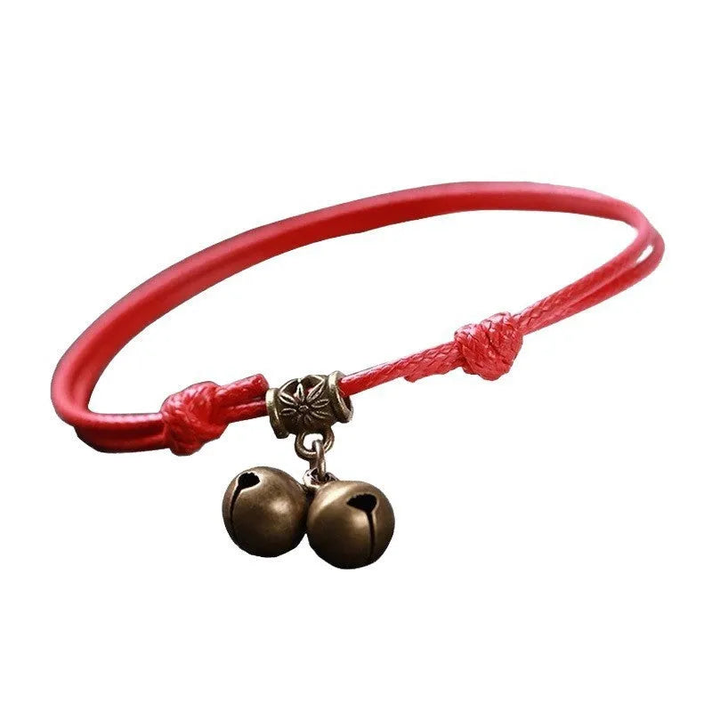 Black nylon rope dog collar with a small brass bell on a wooden background.