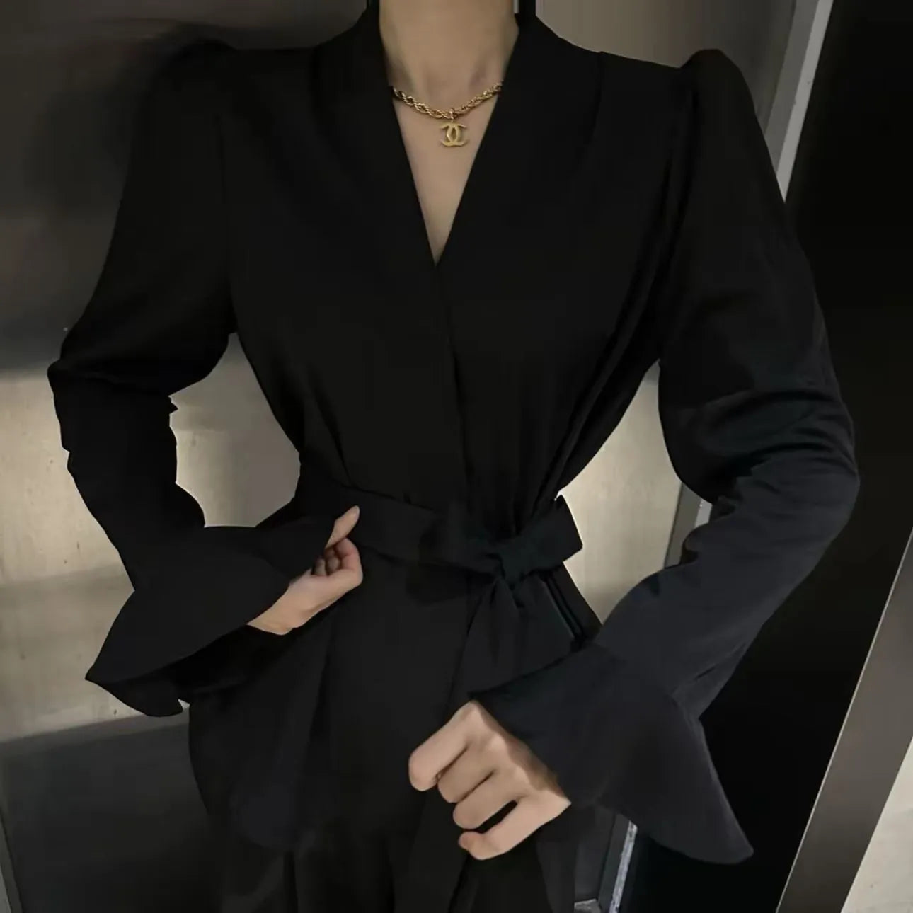 Women's black French-style shirt with irregular collar, long bell sleeves, and tied front detail.