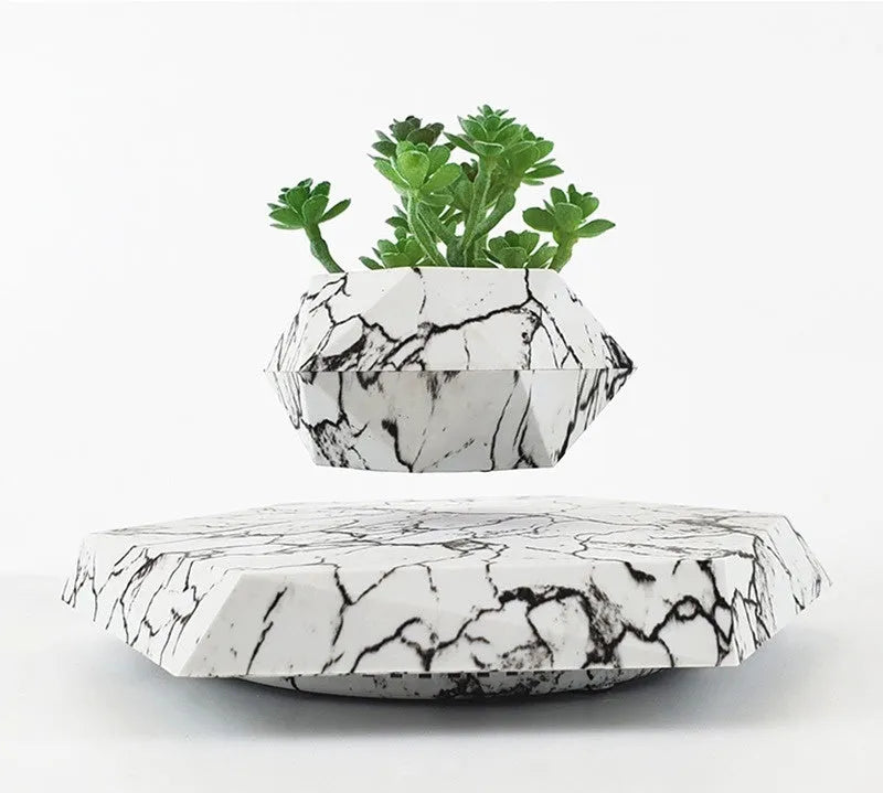 Small marble-colour levitating plant pot floating above its magnetic base on a desk.