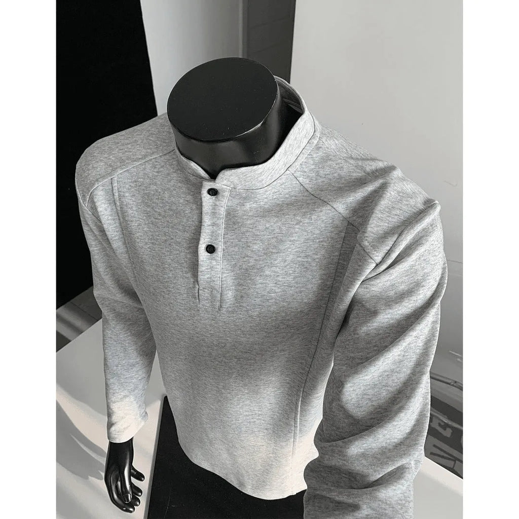 Man wearing a gray long sleeve sweater with a stand-up collar and patchwork design on the shoulders