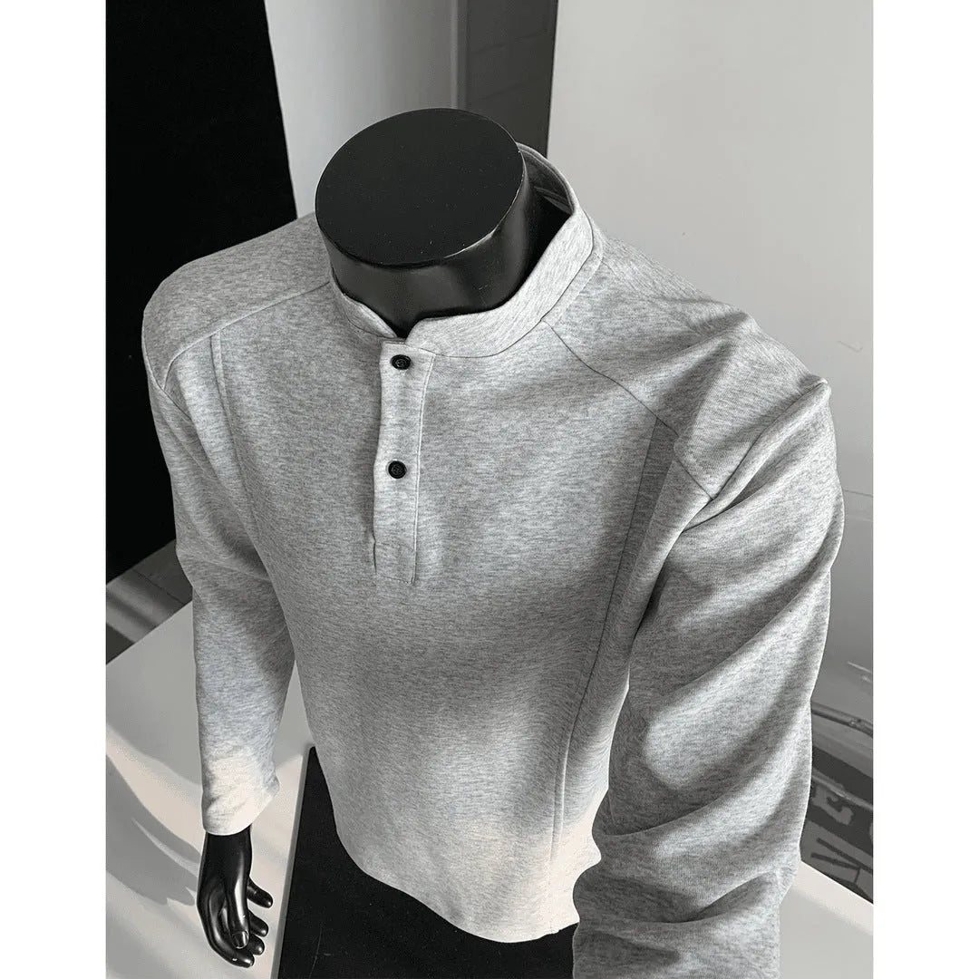Man wearing a gray long sleeve sweater with a stand-up collar and patchwork design on the shoulders