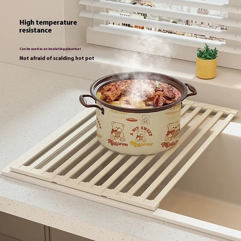 Foldable milky white stainless steel kitchen draining rack with dishes, shown next to a sink.