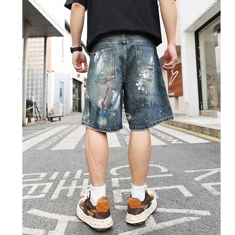 Blue ripped men's denim shorts with graffiti design, showing straight leg and zipper fly.