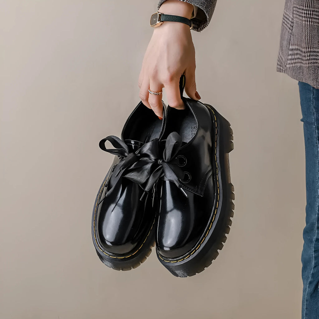 Black women's thick soled lace-up shoes with ribbon and cross strap detail on a superfine fibre upper.