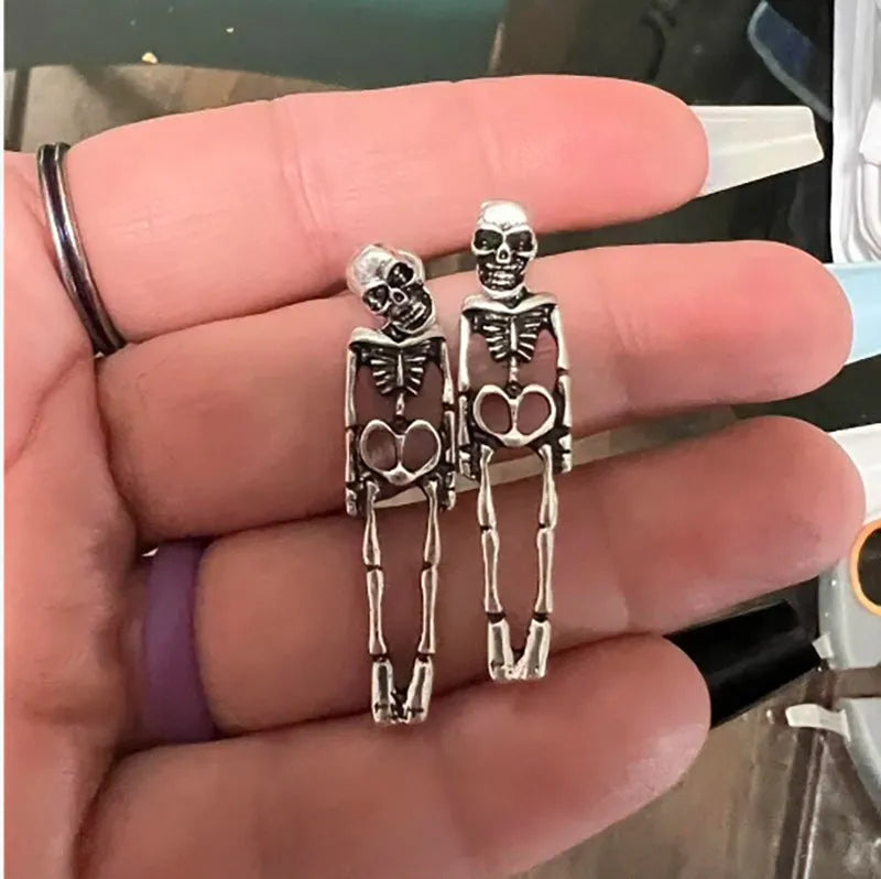 Gold and silver skull detachable stud earrings with skeleton design on white background