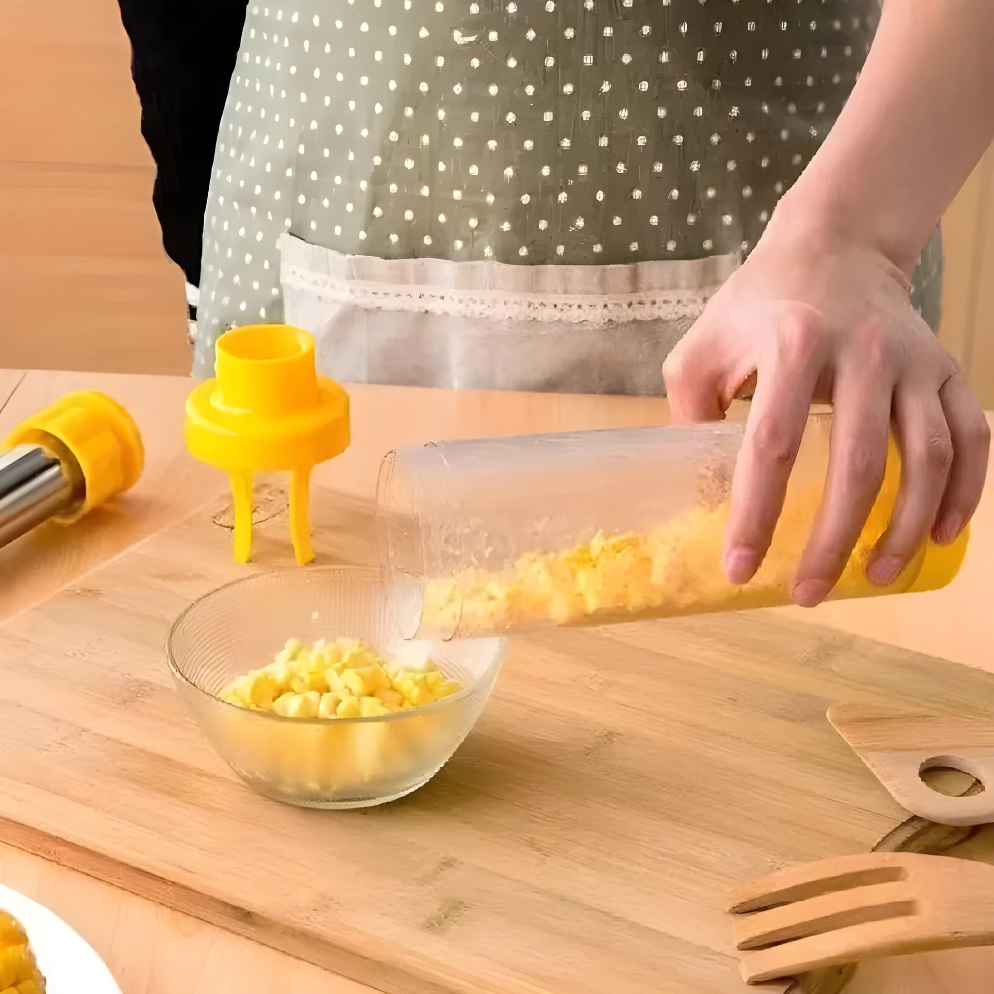 Yellow manual corn stripper thresher with stainless steel construction on a kitchen worktop.