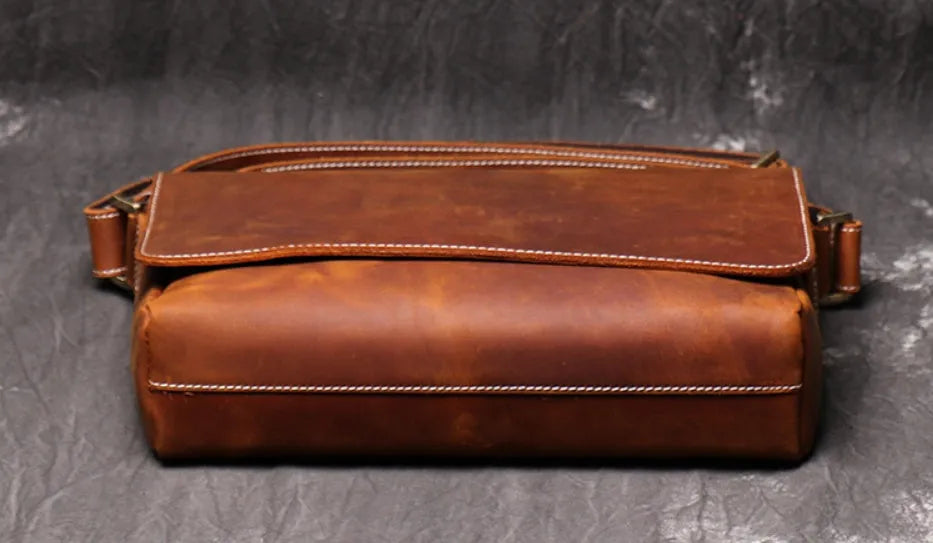 Vintage brown men's leather messenger bag showing interior compartments and adjustable shoulder strap