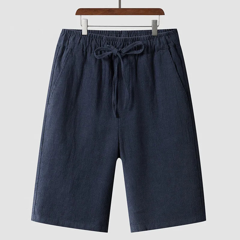 Man wearing beige linen cropped shorts with a loose fit and elasticated waistband.