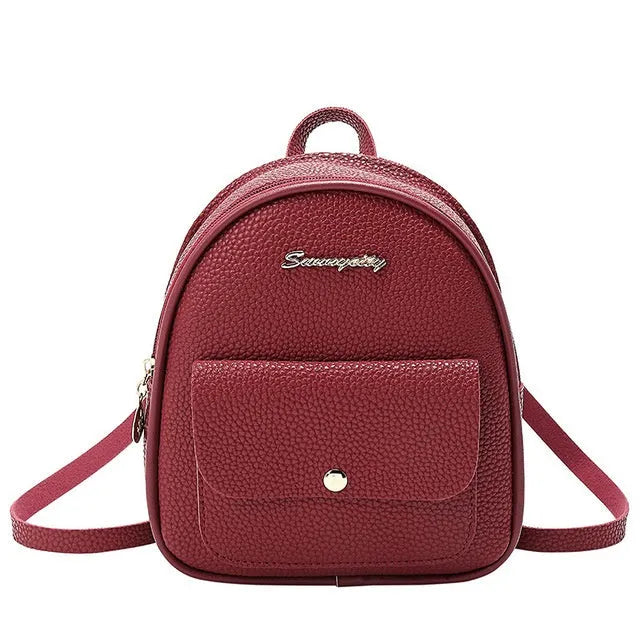 Small black women's backpack shoulder bag with zipper closure shown next to a mobile phone for scale