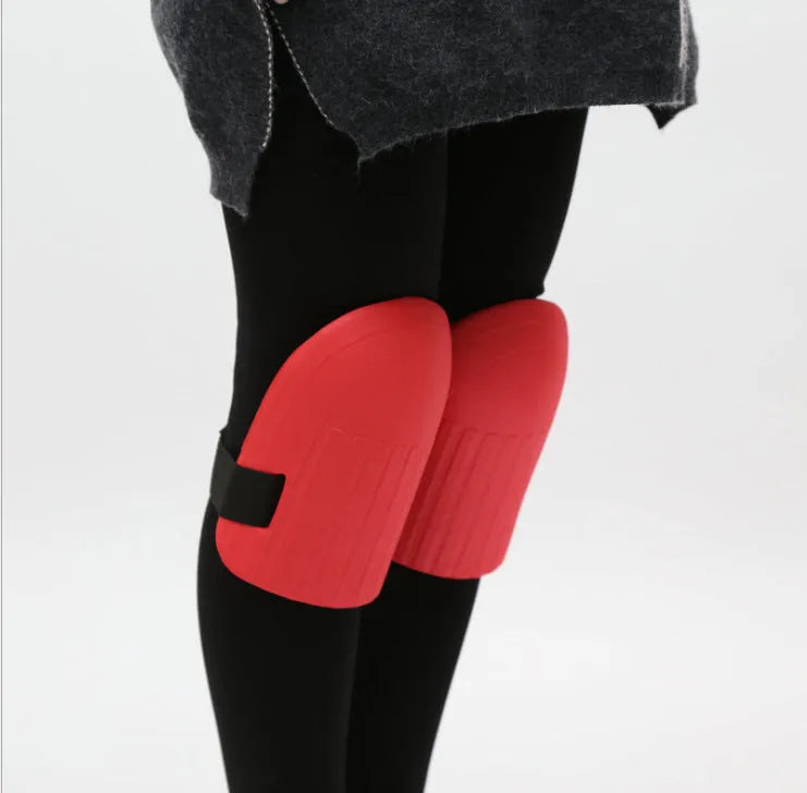 A pair of EVA foam knee pads in army green colour, shown from above on a garden soil background.