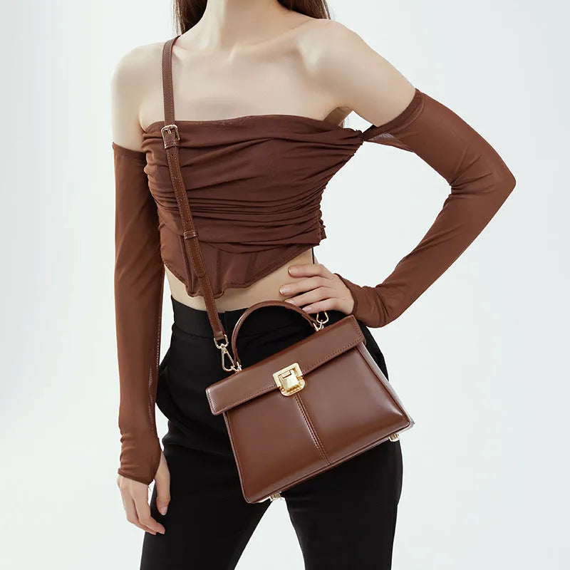 Women's black leather shoulder bag with vachette clasp showing horizontal square shape and adjustable strap