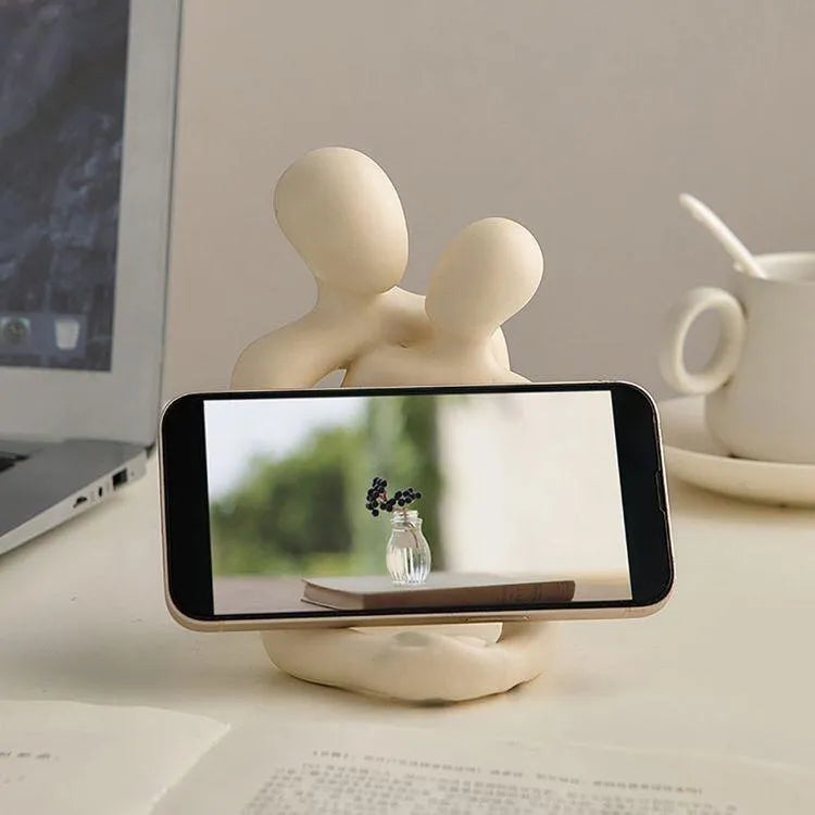 Modern minimalist resin statue of a couple in milky white or gold colour on a wooden surface.