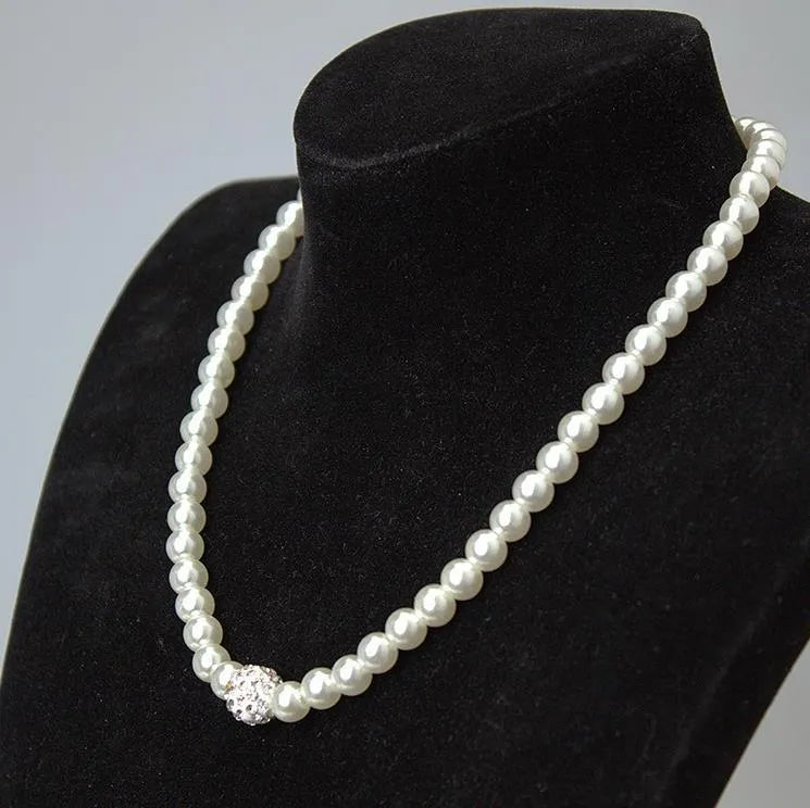 White plastic resin pearl-style jewellery set including necklace, earrings, and bracelet on display