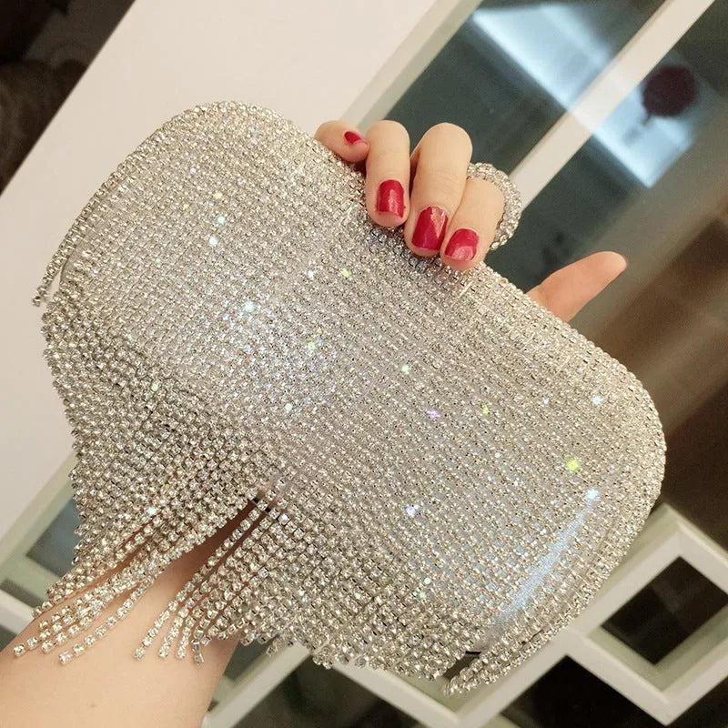 Silver ladies fringed hand bag with shiny diamond embellishments and clasp closure on a plain background
