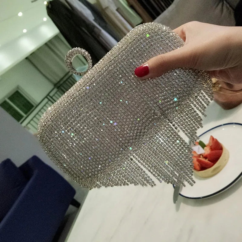 Silver ladies fringed hand bag with shiny diamond embellishments and clasp closure on a plain background