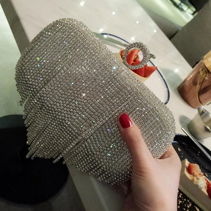 Silver ladies fringed hand bag with shiny diamond embellishments and clasp closure on a plain background