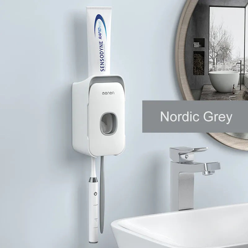 Wall-mounted automatic toothpaste dispenser in blue, grey, or pink colours with a visible dispensing lever.