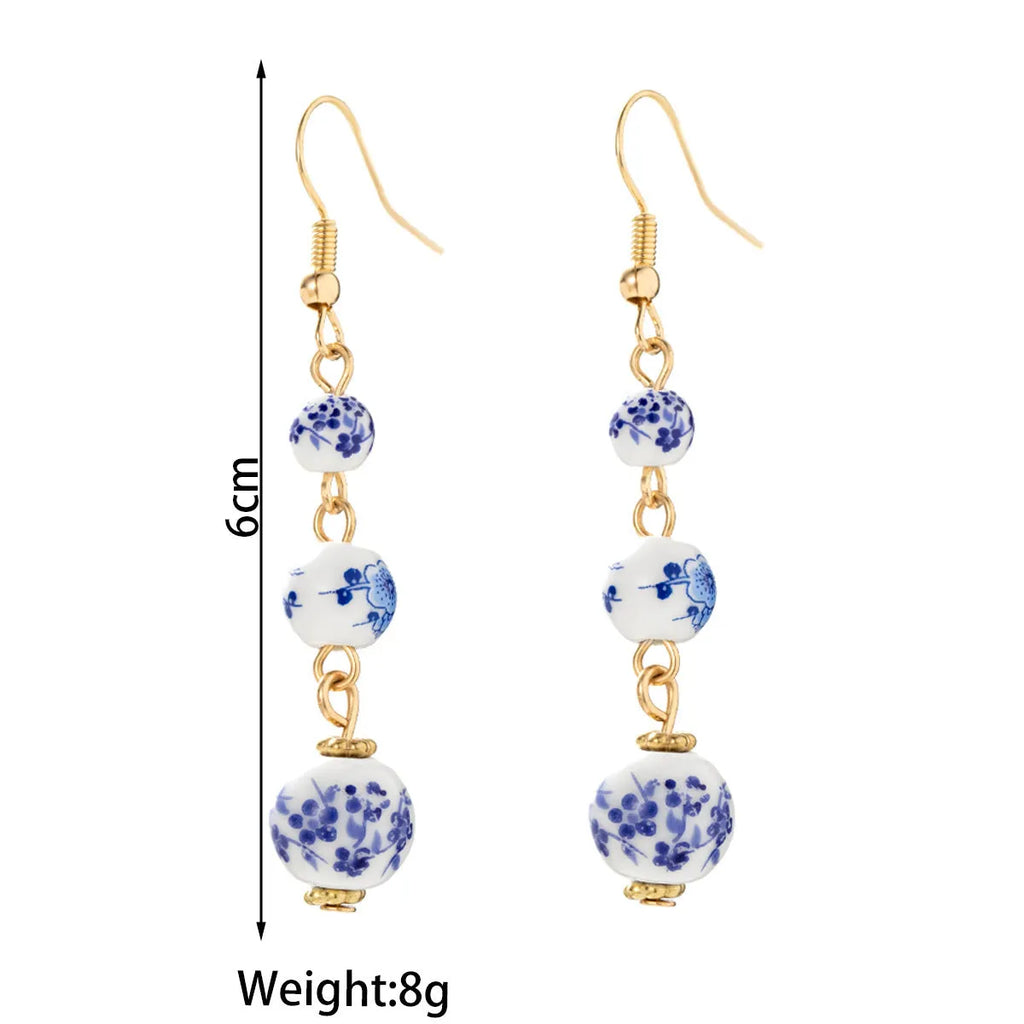 Long retro earrings with blue and white porcelain-coloured ceramic beads and geometric alloy details.