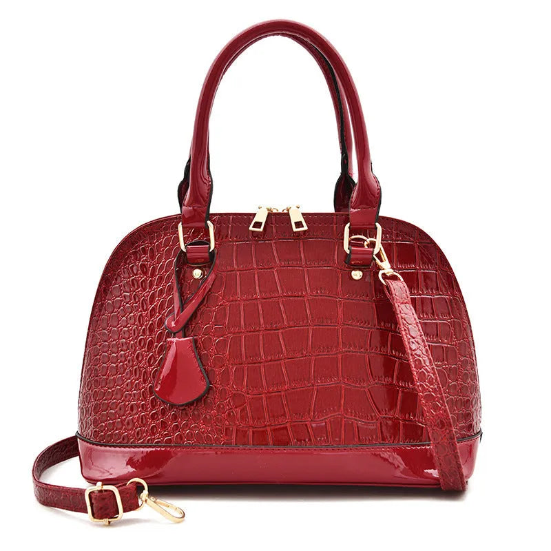 Shiny black PU leather crossbody bag with a structured shell shape, shown with a shoulder strap.