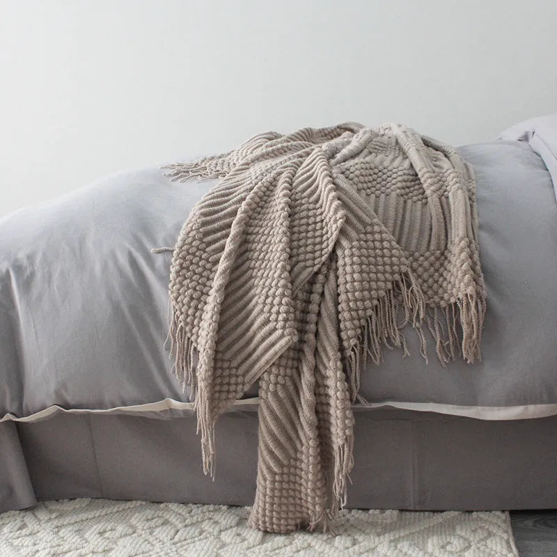 Small polyester fibre throw blanket in dark grey, folded on a sofa