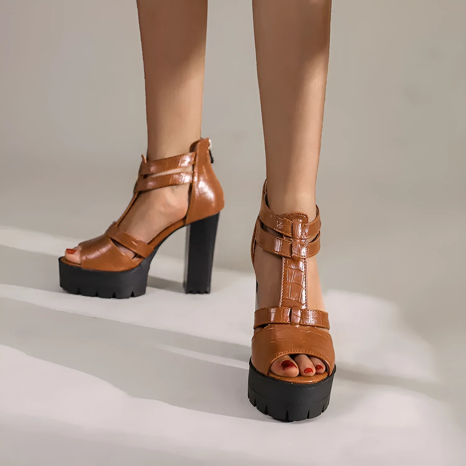 A pair of black platform high heel sandals with a back zipper and round toe on a rubber sole.
