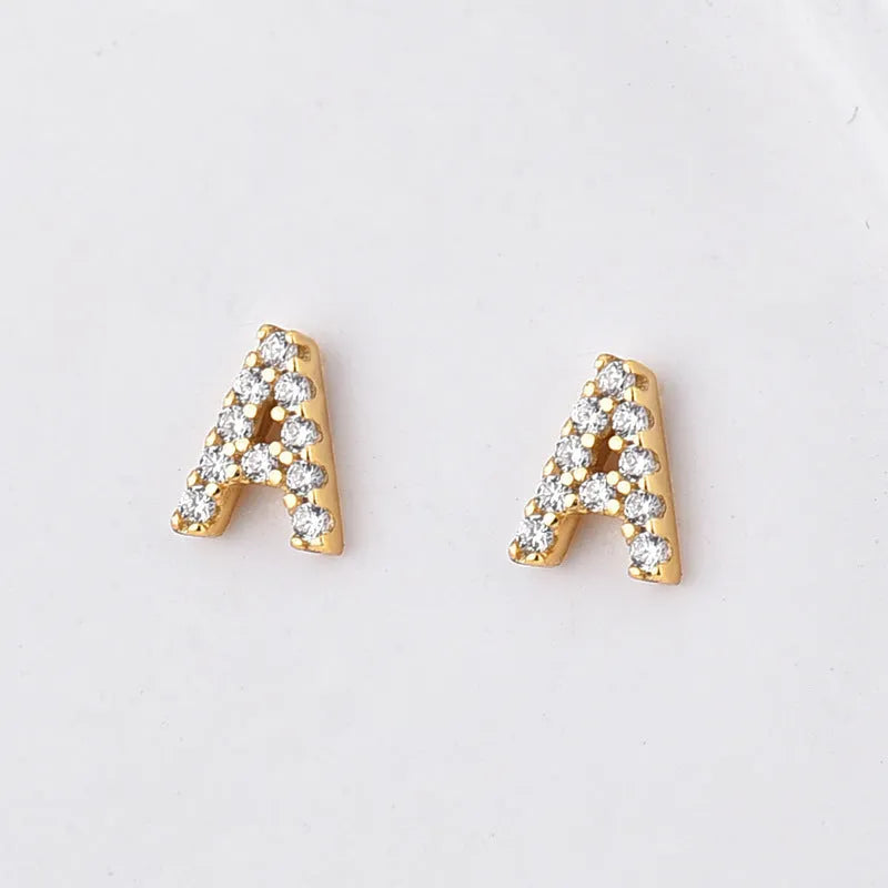 Gold plated brass alphabet letter earrings on a white background, showing zircon detail.