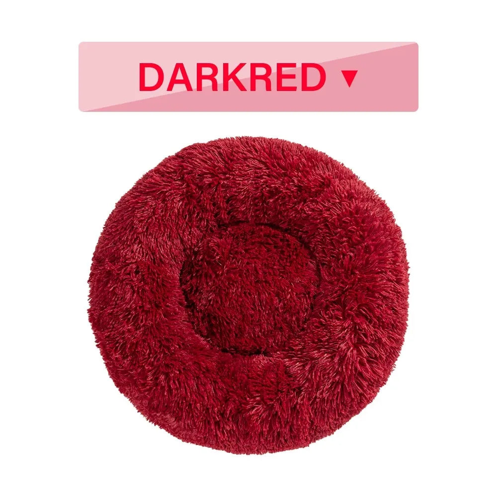 Fluffy grey donut-shaped dog bed with raised plush edge on a wooden floor.