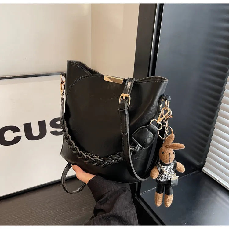 Women's retro PU messenger bag in brown with compact bucket shape, pendant, and double shoulder strap connector