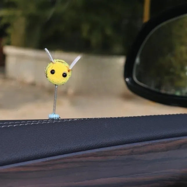 Small, soft, cartoon bee car decoration made from yellow and black fur ball material.