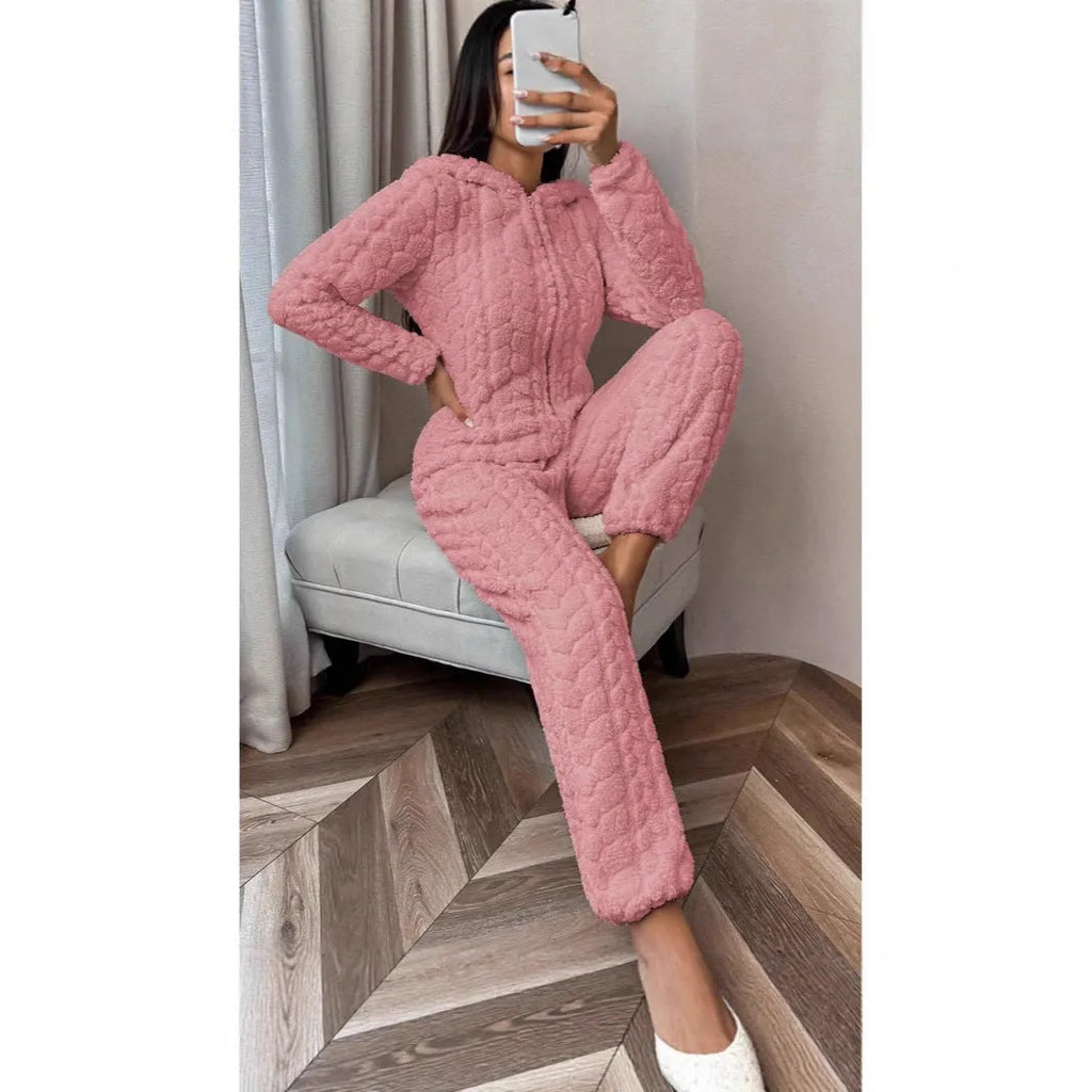 Beige hooded thickened coral fleece one-piece pajama with long sleeves on a woman standing indoors