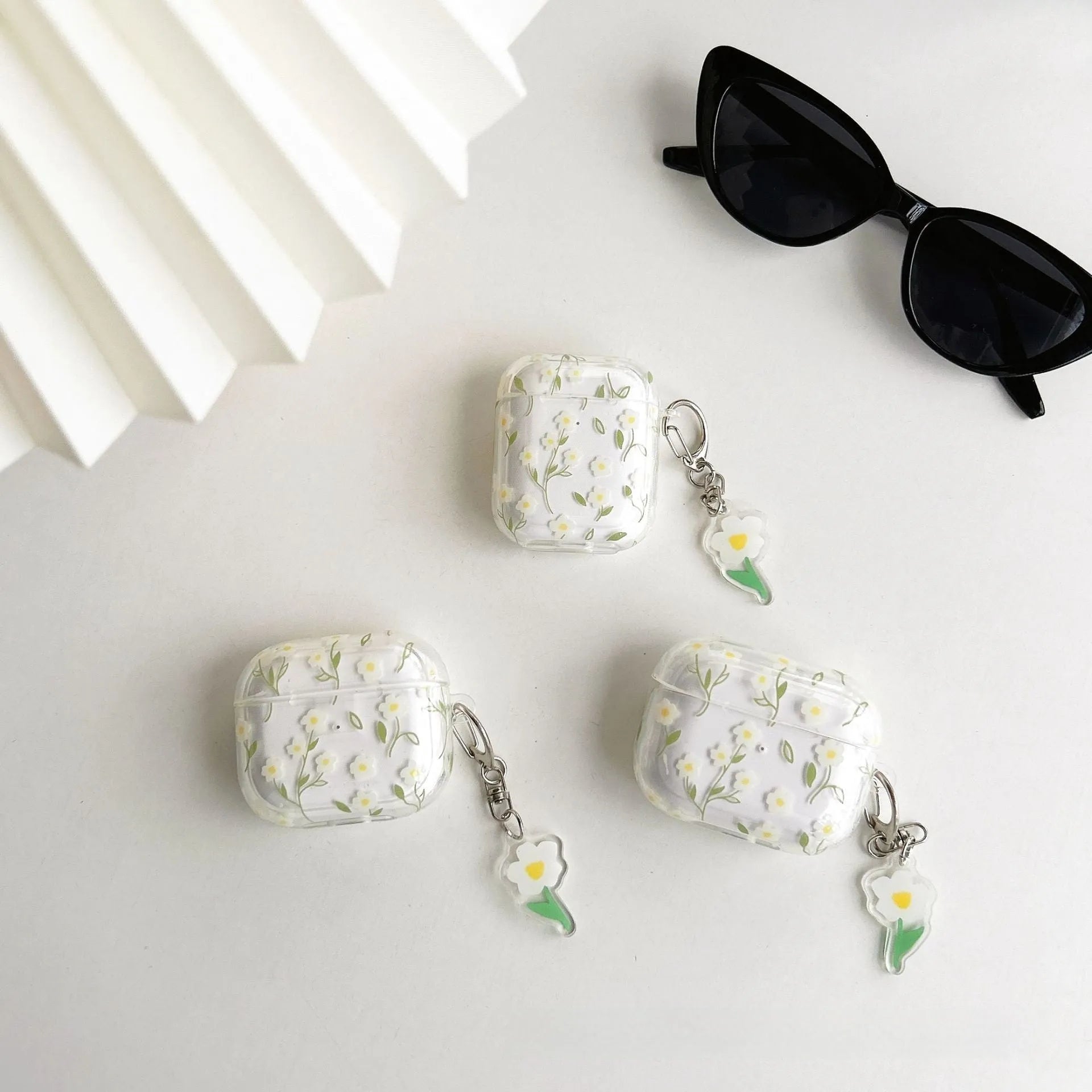 Transparent white floral TPU protective case for Apple AirPods headphones on a table.