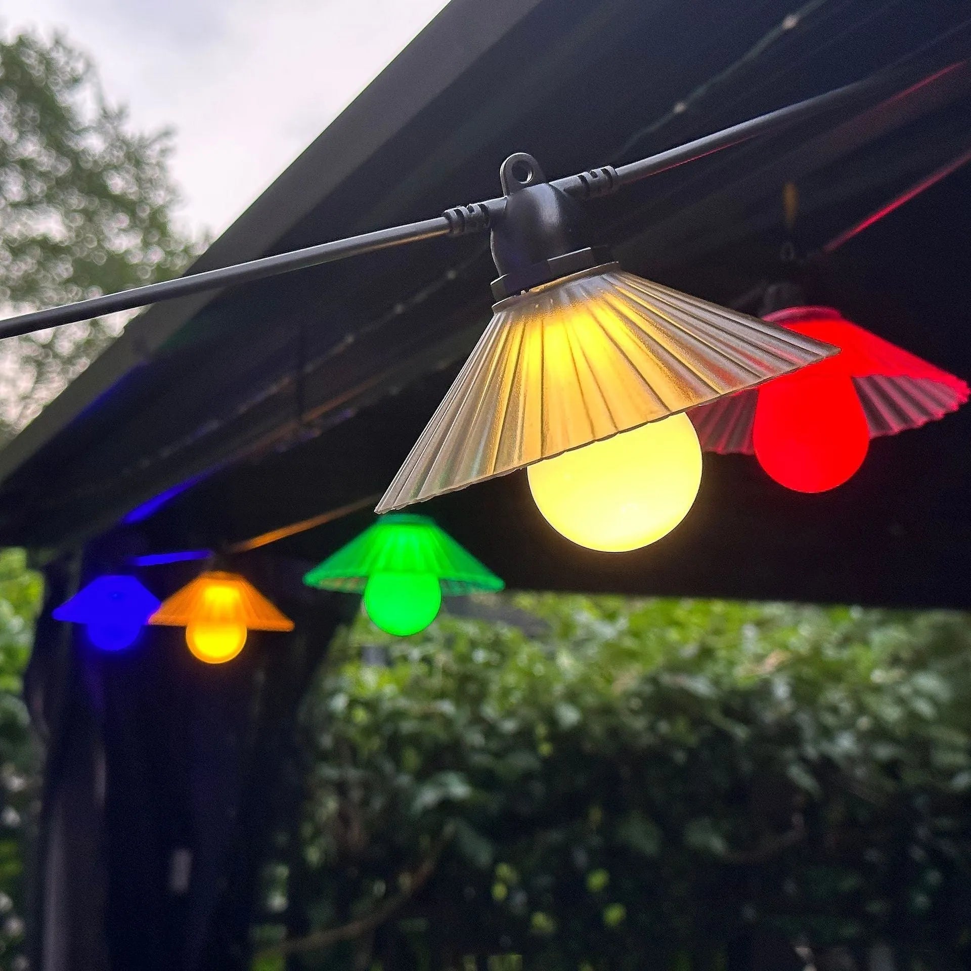 Outdoor LED string lights with white flower-shaped bulbs hanging in a garden.