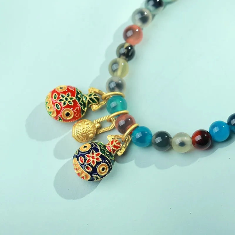 Natural agate and coloured glaze snake bracelet with copper coin charms on a white background.