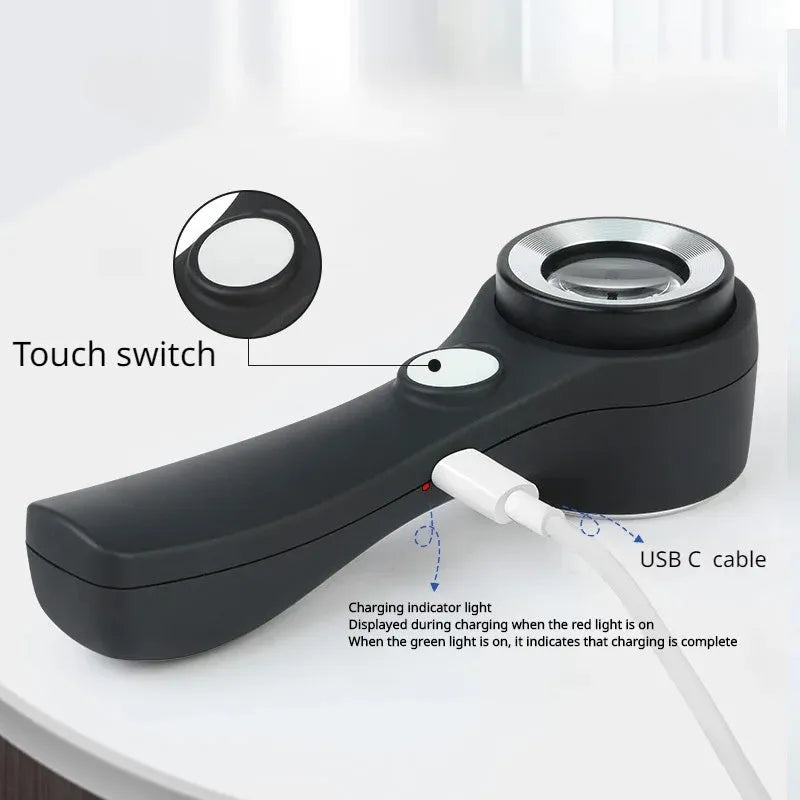 Black and silver handheld appraisal magnifying glass with optical glass lens and USB-C cable on a table.