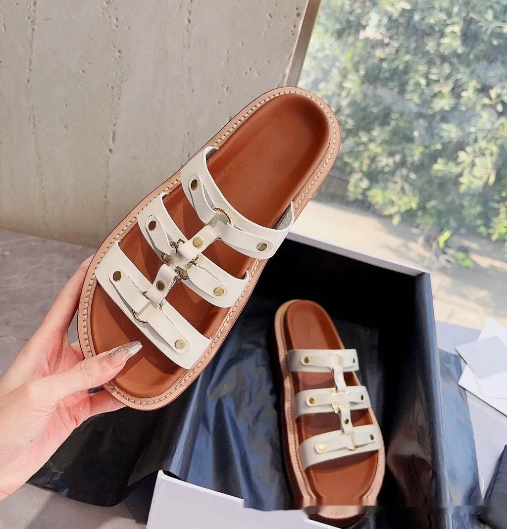 Women's brown retro Roman strap sandal slippers made from sheepskin and patent leather on a wooden floor.