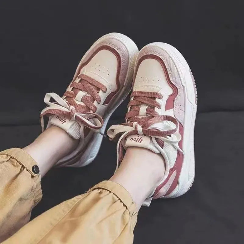 Pink and white low-top sneaker with a height-increasing rubber sole.