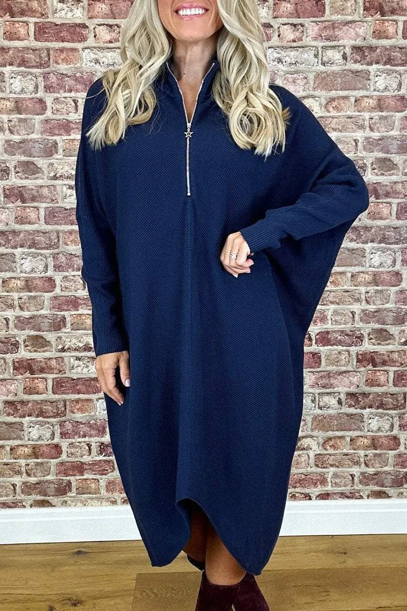 A woman wearing a loose-fitting solid colour knitted dress with raglan sleeves and a front zipper.