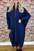 A woman wearing a loose-fitting solid colour knitted dress with raglan sleeves and a front zipper.