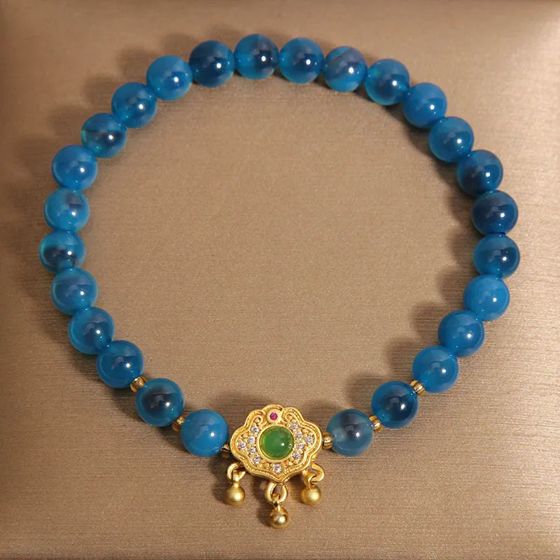 Close-up of a women's blue sugar heart agate safety lock pendant bracelet with crystal links and rhinestone detailing.