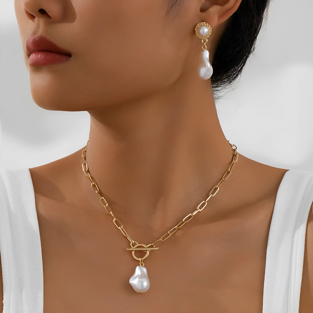 Gold-colour iron necklace and earring set with a baroque pearl pendant on a woman.