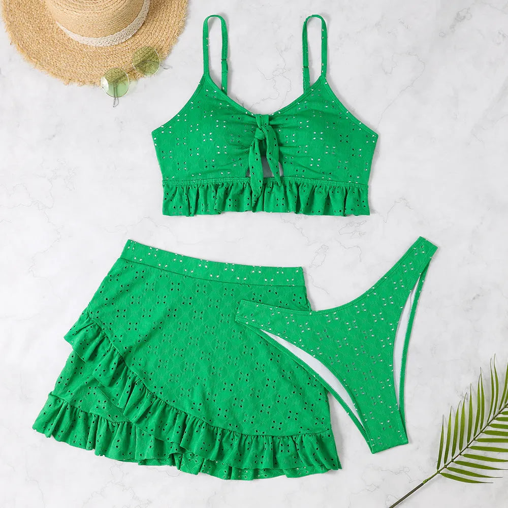 Women's white three-piece bikini set with a split hip skirt, made from polyester.