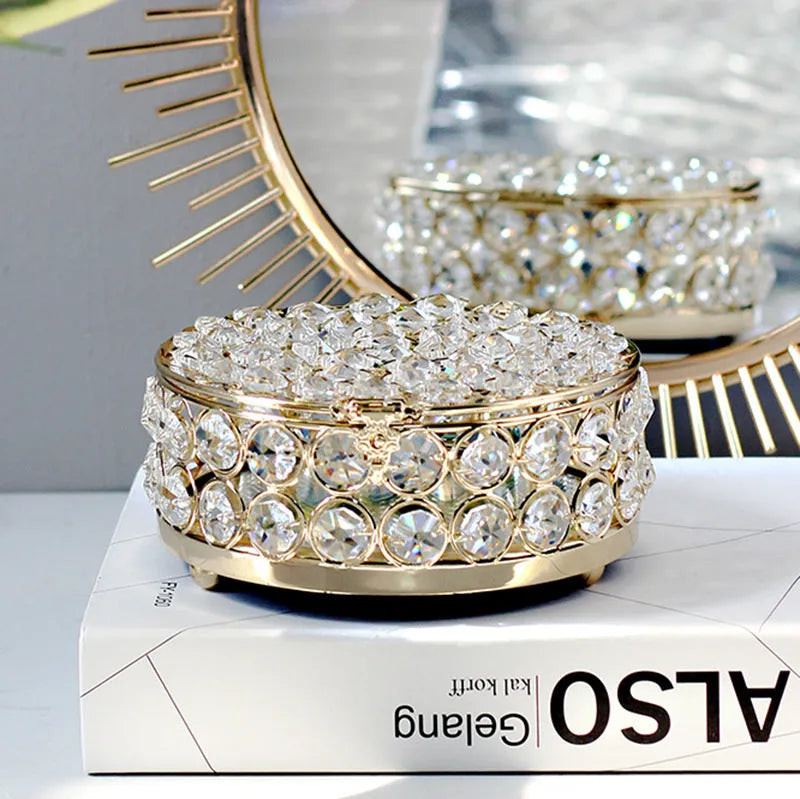 French gold iron jewellery box with a clear crystal glass lid on a wooden surface.