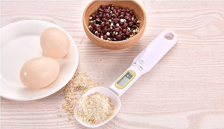 Black electronic measuring spoon scale with digital display on handle and integrated spoon bowl.