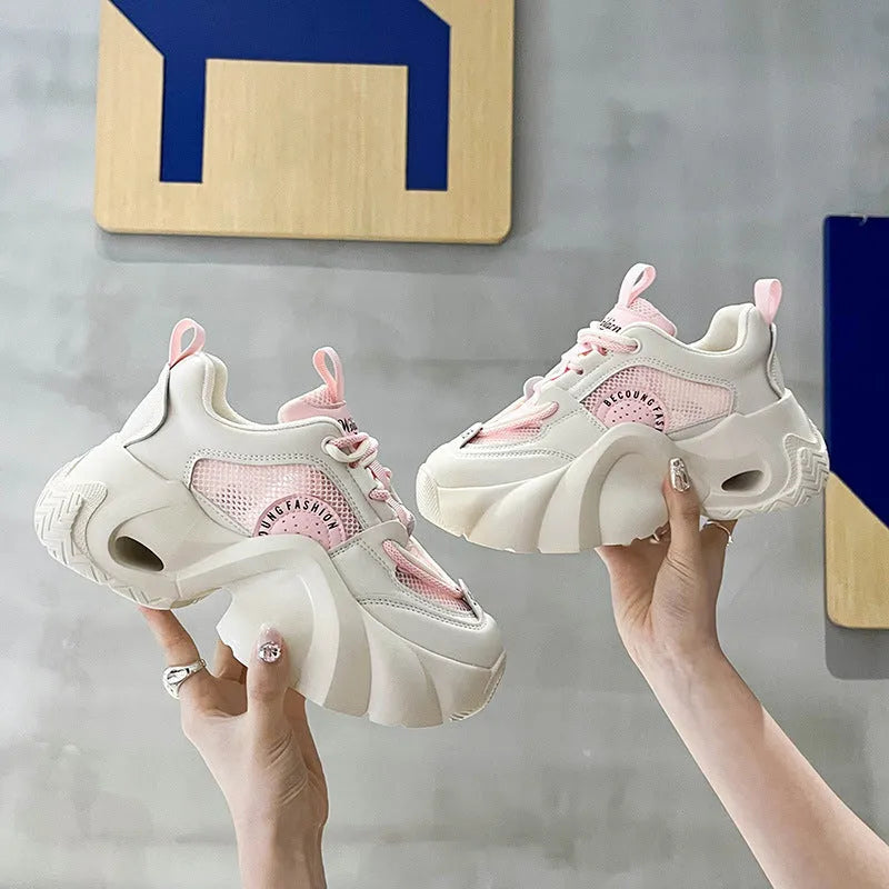 Women's pink sneakers with cross shoulder straps, thick sole, and mesh lining on a white background.