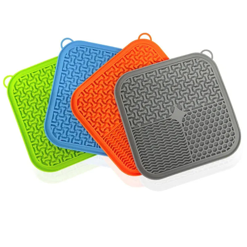 Orange red silicone dog lick mat with suction cups on a smooth surface.