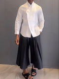 White asymmetric long sleeve shirt paired with black pleated pants in a women's casual two-piece set.