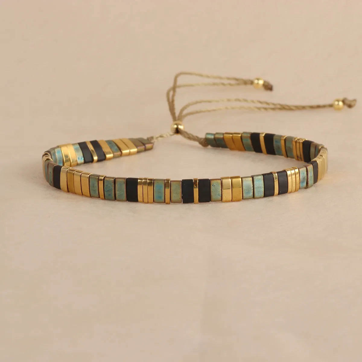 Geometric glass and coloured glaze beaded bracelet with a pull clasp in milky white colour.