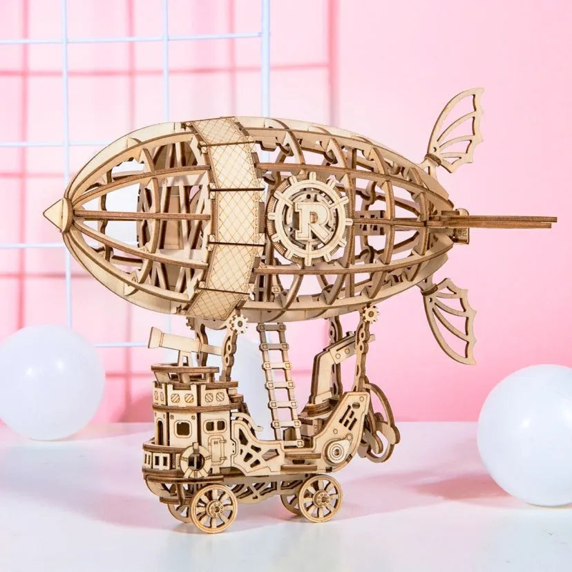 Four wooden 3D puzzle models showing an Airship, Balloon, Radio, and Pumpkin Carriage