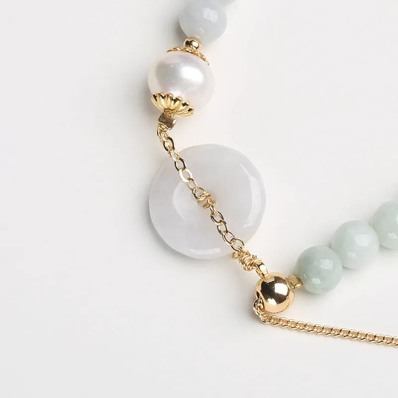 Natural green jade and pearl bracelet with peace buckle closure on wrist
